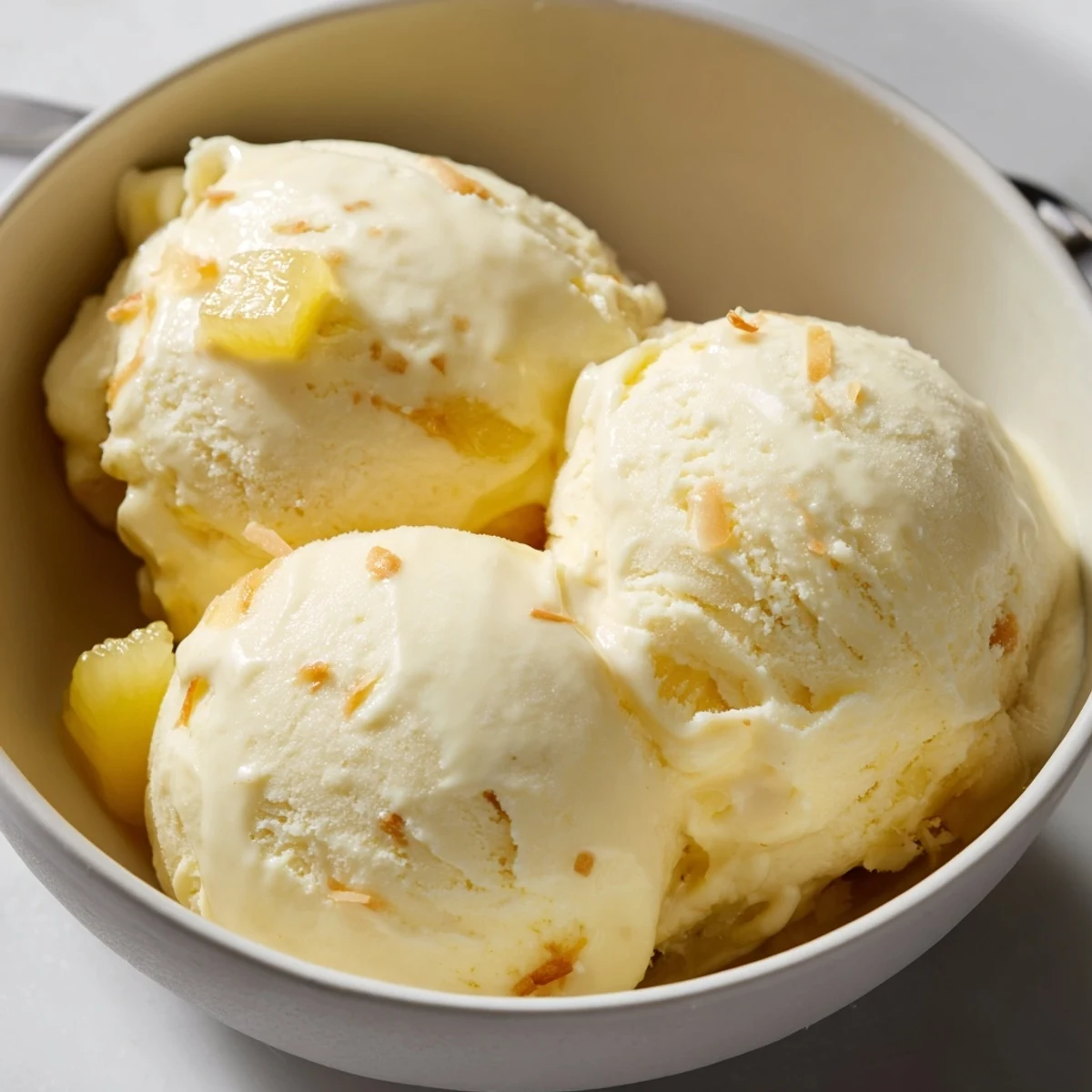 A bowl of Creamy Pineapple Ice Cream Recipe garnished with toasted coconut