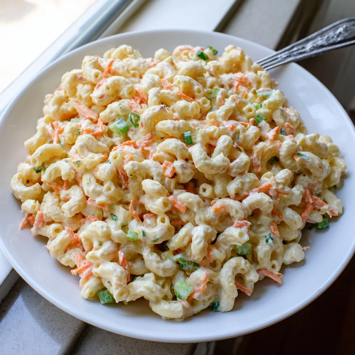 Hawaiian style mac salad featuring tender elbow macaroni coated in tangy mayonnaise dressing with green onion garnish