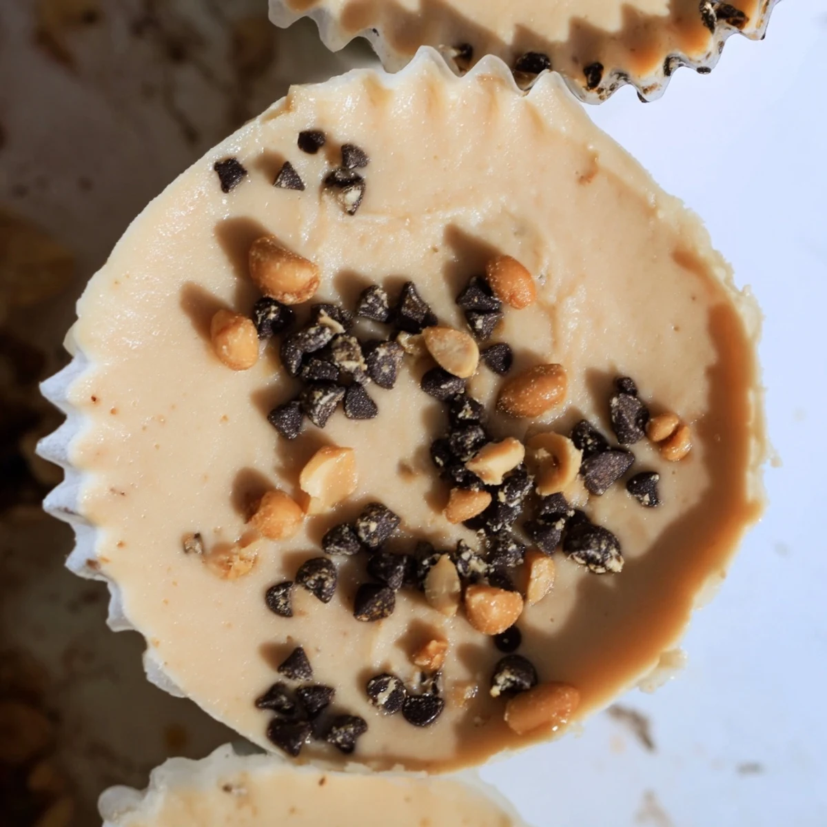 Golden brown high protein frozen peanut butter Greek yogurt bites arranged on a white plate with chocolate chip garnish