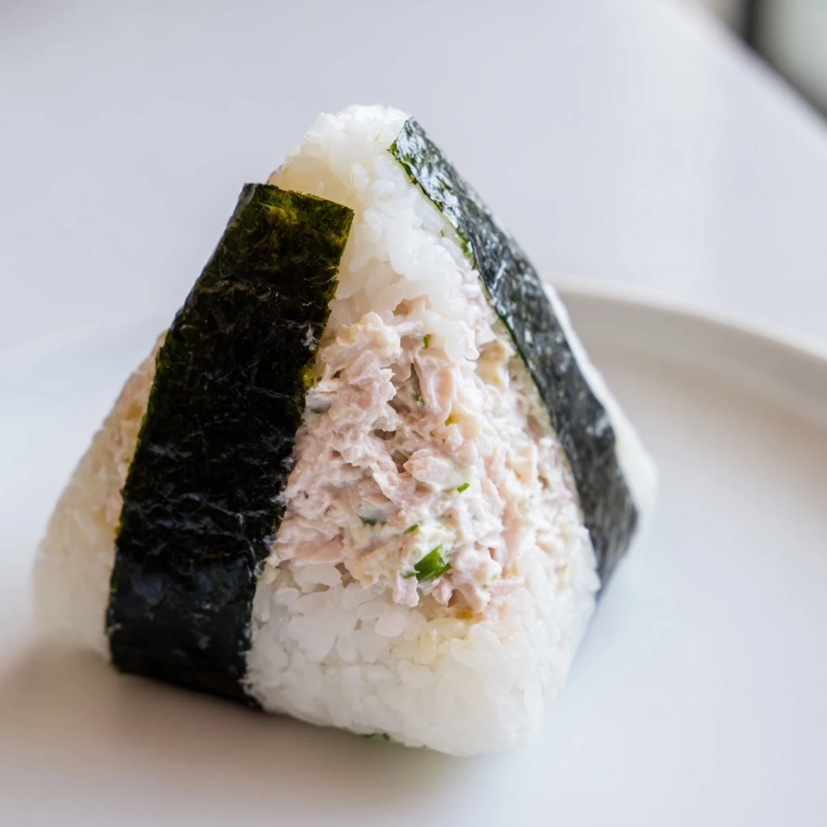 Handheld Japanese rice ball stuffed with creamy tuna mayonnaise filling ready for lunchbox