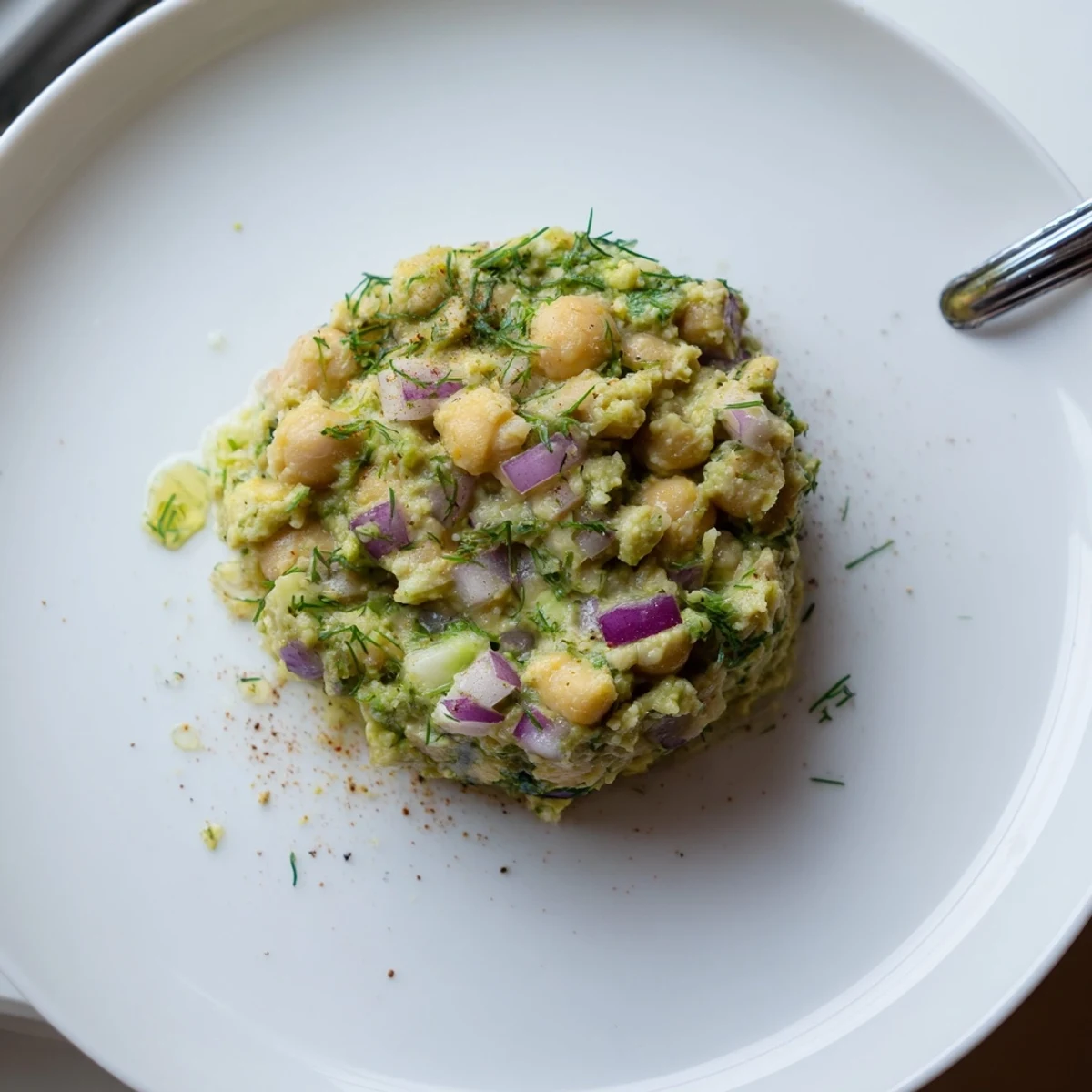 Small bowl of Smashed Chickpea Avocado Pickle garnished with cilantro, lemon