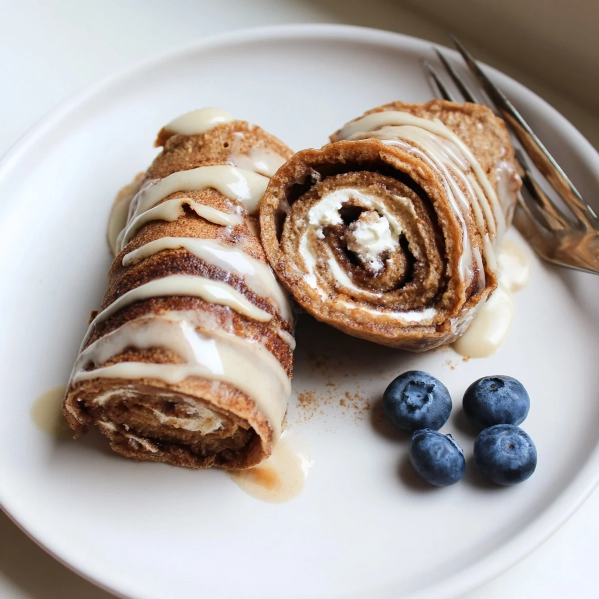Cinnamon Roll Protein Crepes Recipe drizzled with glaze, warm and soft texture
