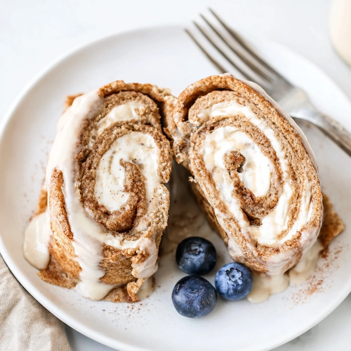 Stack of Cinnamon Roll Protein Crepes Recipe, cream-filled spirals, lightly dusted cinnamon
