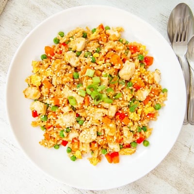Sizzling Bang Bang Fried Rice in a skillet, garnished with sesame seeds and green onions.