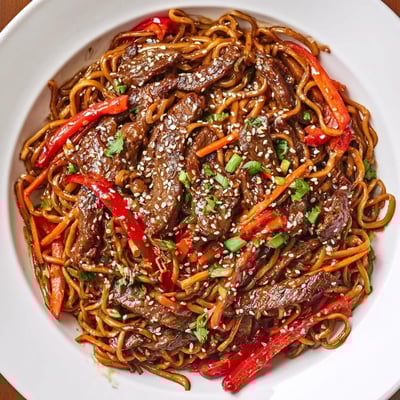 Plate of Sticky Beef Noodles tossed with crisp bell pepper and glossy sauce